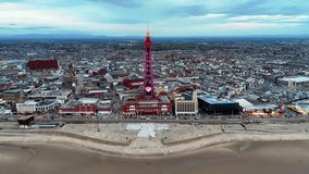 Aerial drone push-in towards the iconic Blackpool Tower, illuminated pink with a heart, overlooking the city and beach at dusk - Powered by Shutterstock - Get 15% off with code: PIKWIZARD15