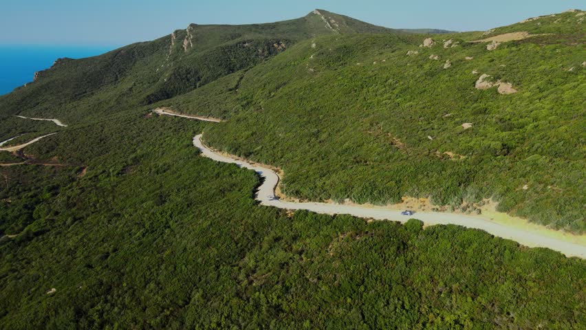 Aerial view of a scenic road winding through lush green hills and mountains in Tunisia.