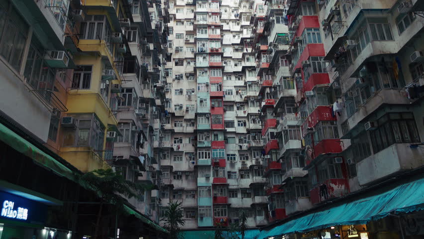 breathtaking vertical view of an iconic housing complex in Hong Kong. Showcasing densely packed residential buildings with balconies, air conditioning units, and colorful facades