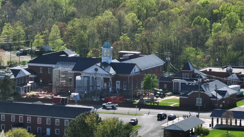 Aerial approaching shot showing renovation of famous and historic Court House in Appomattox, Virginia. Sunny day with car on street. Historic building of civil war.