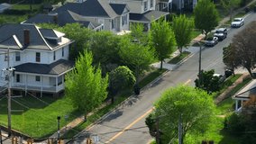 Quaint charming neighborhood in American with traditional american two-story houses. Sunny day with green trees in spring season. Aerial wide shot. Parking cars along street. - Powered by Shutterstock - Get 15% off with code: PIKWIZARD15