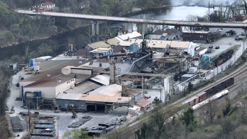Aerial view of U.S. Pipe Factory in Lynchburg near James River. Railway tracks in suburb. Bridge in background. Virginia, Usa. Cloudy day in spring.