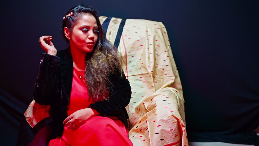Girl Modeling on Chair in Indoor Studio Setup, Woman Posing for Portfolio at Photography Office, Female Artist Smiles Under Colorful Cabin Light, Chic performer works poses into bright lit environment