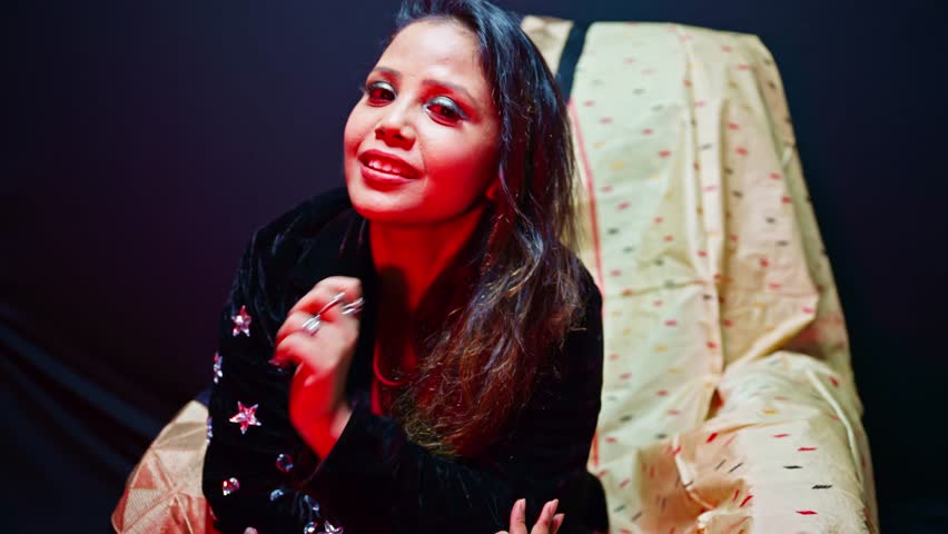 Woman Posing for Portfolio at Photography Office, Girl Modeling on Chair in Indoor Studio Setup, Female Artist Smiles Under Colorful Cabin Light, Chic performer works poses into bright lit environment