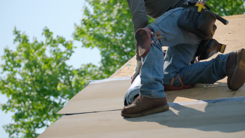 Roofer installing a new roof covering with glue surface. Self-Adhering Roofing System process.