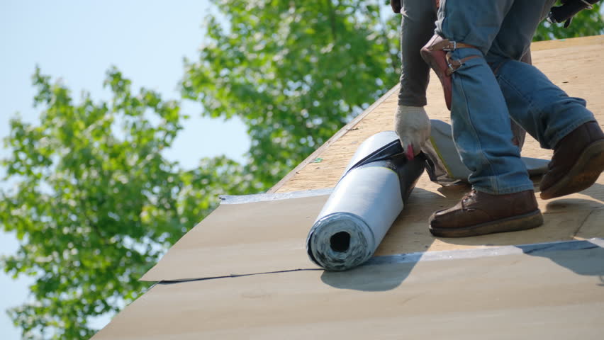 Roofer installing a new roof covering with glue surface. Self-Adhering Roofing System process.