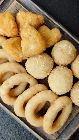 Food, chicken nuggets, onion rings and cheese balls on dark background. Fast food, unhealthy lifestyle