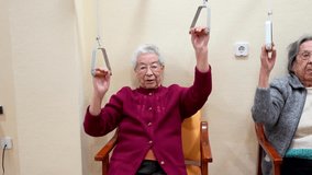 Senior women performing arm strengthening exercises with pulley equipment under nurse supervision, focusing on mobility and wellness in nursing home rehabilitation setting - Powered by Shutterstock - Get 15% off with code: PIKWIZARD15