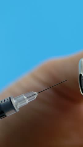 Medical assistant hand handles syringe while withdrawing liquid from vial. Vaccination concept. Healthcare system support. Proper medical handling ensuring patient safety and well being