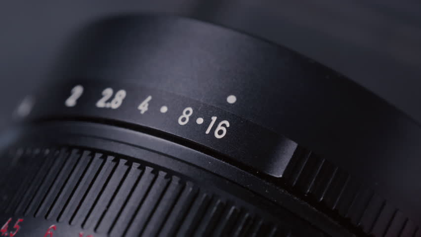 Closeup: Aperture ring changing on camera old Lens, adjusting F-Stop number and iris, showing aperture scale and ring shifting. Professional photographer adjusting lens aperture stop. Close up shot