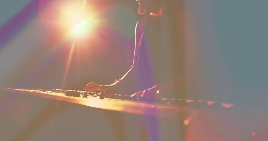 woman playing keyboard on dark stage, vivid backlighting, lens flares, smoke in music performance. Performance, concert, nightlife, lighting, atmosphere, energy, music