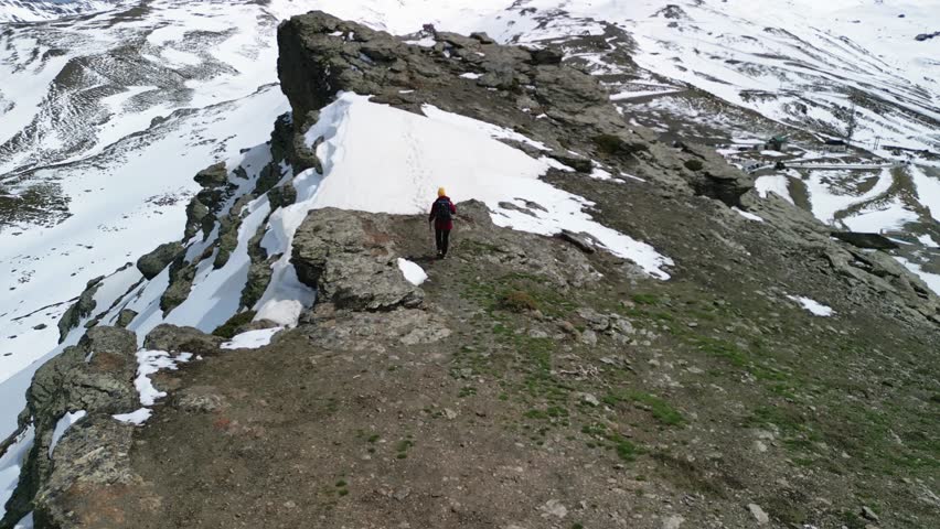 Mountaineer walking on a snowy mountain ridge

