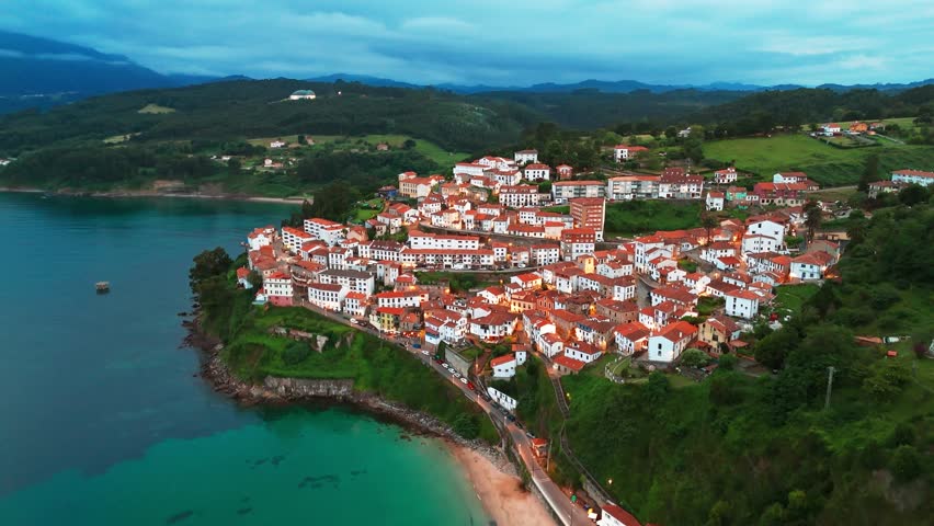 Aerial view of the charming fishing village of Lastres in the Asturias region at twilight, northern Spain. A beautiful coastal town nestled on a hillside overlooking the Bay of Biscay.