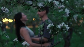 Romantic young couple kissing at sunset in blooming spring garden. Tender love scene surrounded by flowering apple trees and soft bokeh lights. Emotional moment of affection and intimacy outdoors. - Powered by Shutterstock - Get 15% off with code: PIKWIZARD15