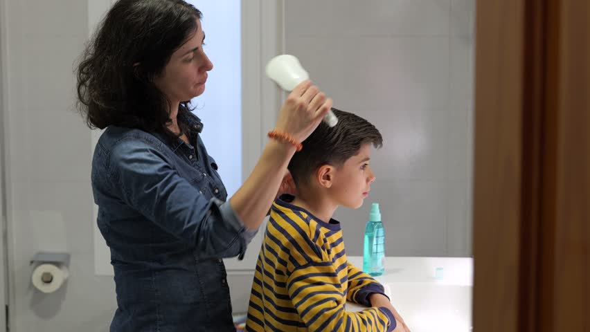 mother combing son at home bathroom