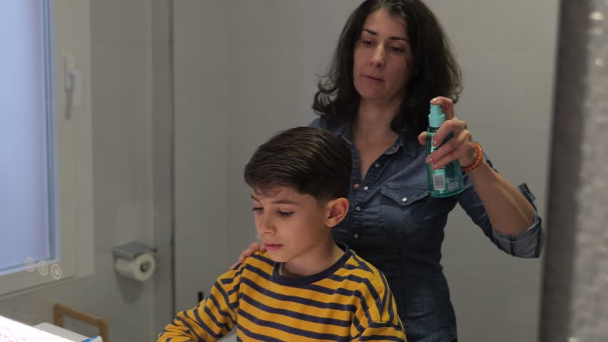 mother combing son at home bathroom