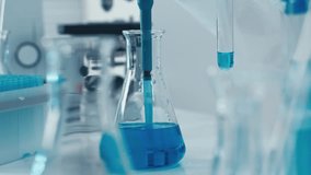 In a wellequipped lab, a skilled technician uses a pipette to transfer vibrant blue liquid between test tubes and flasks, showing precision in chemical analysis and experimentation techniques - Powered by Shutterstock - Get 15% off with code: PIKWIZARD15