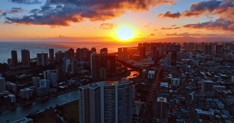 Fantastic bright sun setting above the horizon of the Pacific Ocean waterscape. Drone flight above the scenery of Honolulu, Hawaii, USA.