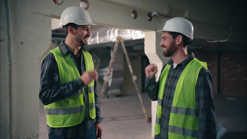 Two Caucasian men colleagues workers builders playing hands gestures scissors paper stone friends co-workers team males guys buddies engineers construction building cooperate constructors play game