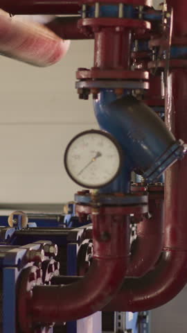 Metal pipes with manometers and powerful pumps in mechanical room. Heat generating system installed in modern building basement. Temperature adjustment
