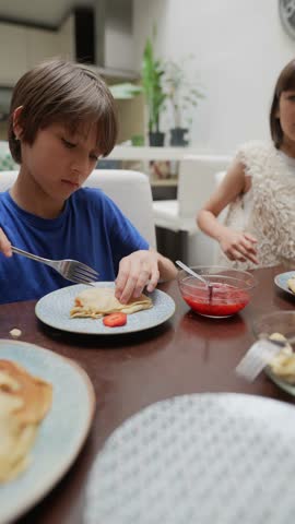 Children Having a Great Time Relishing Delicious Pancakes At Their Breakfast Table Together