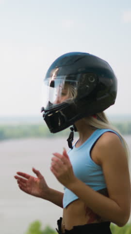Happy man and young woman in blue top take off protective moto helmets standing against large picturesque lake on spring day slow motion