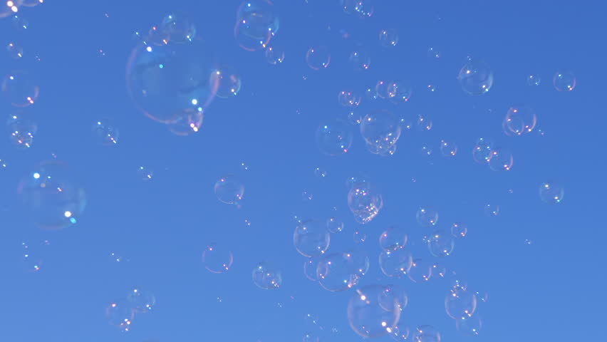 Soap bubbles rise towards a clear blue sky, creating a whimsical and dreamy atmosphere. Ideal for backgrounds, overlays, and joyful projects.