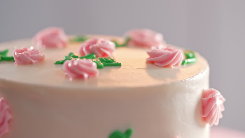 Elegant rotating cake,pink buttercream flowers on white frosting. Bakery, pastry