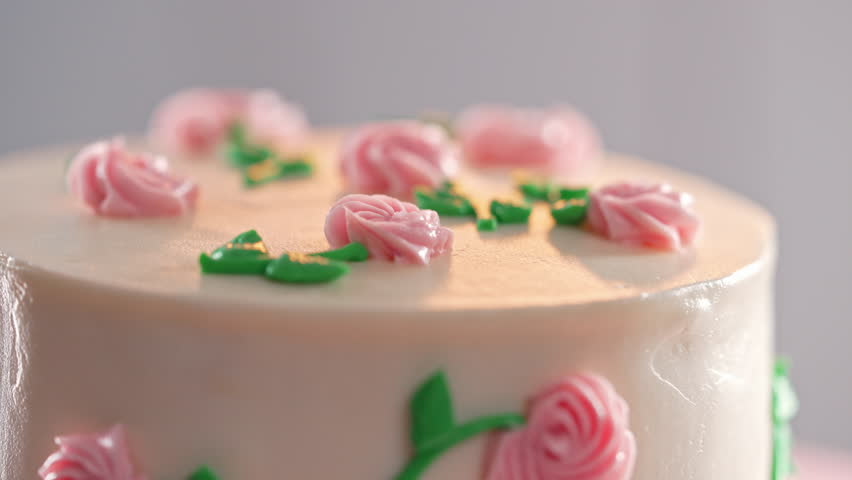 Elegant rotating cake,pink buttercream flowers on white frosting. Bakery, pastry