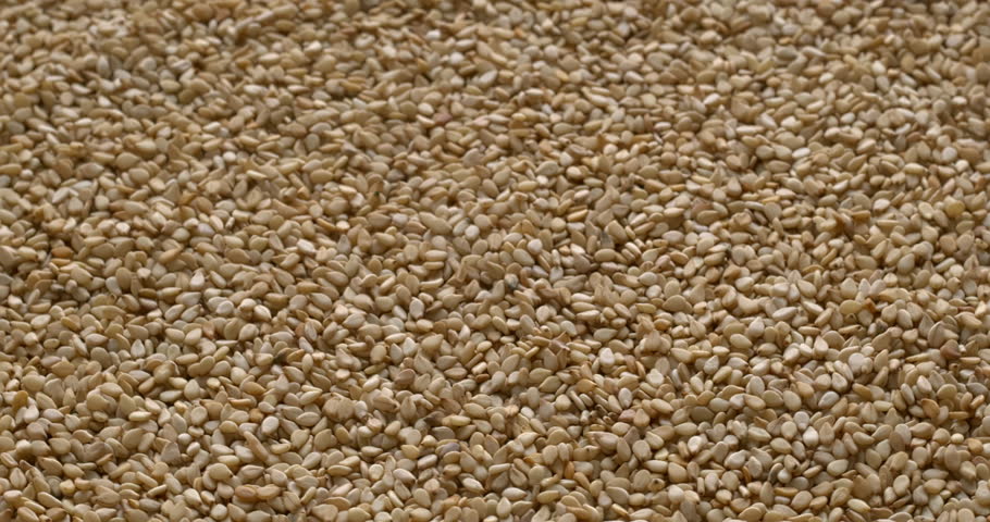 Unhulled sesame seeds background texture. A common ingredient in cuisines worldwide. Selective focus. Table spin.