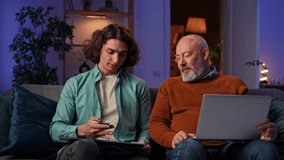 An Older man uses a laptop while a younger man shows how to draw on a graphics tablet. A grandson teaches a grandfather how to design drawing. Collaboration and learning. Slow motion - Powered by Shutterstock - Get 15% off with code: PIKWIZARD15
