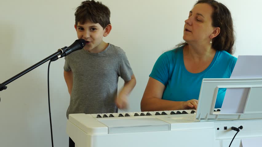 Music lesson. Boy is sings the song and learns to play piano