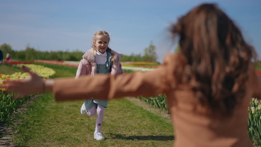 In a vibrant tulip garden, a heartwarming embrace takes place between a loving parent and their child