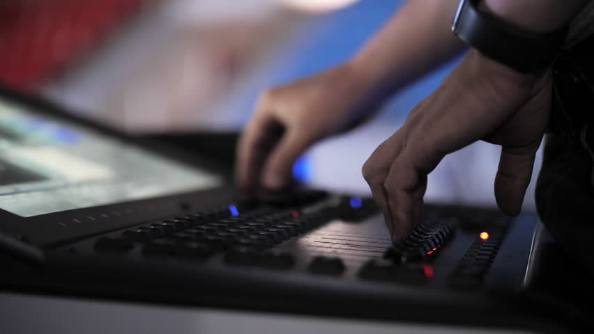 Hand adjusting controls on stage lighting console