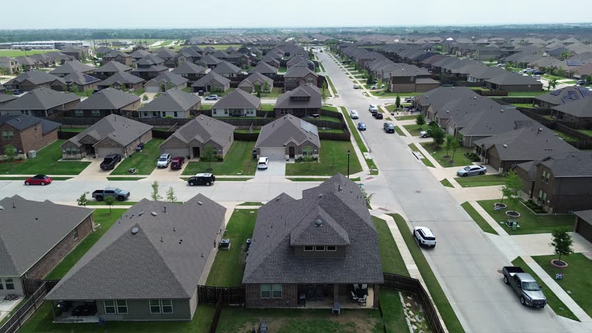 New construction two story houses solar roofing along large residential street, Myrick Lane in Princeton suburbs Dallas, upscale suburban homes in fast growing Collin County, North Texas, flyover. USA