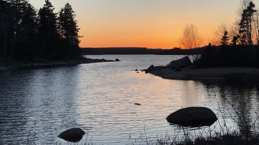 Gorgeous Footage of an Orange Sunset Sky Reflecting in a Calm Lake Near Halifax, Nova Scotia. The Mirror-Like Water Surface Perfectly Reflects the Forests, Creating a Beautiful, Peaceful Landscape.