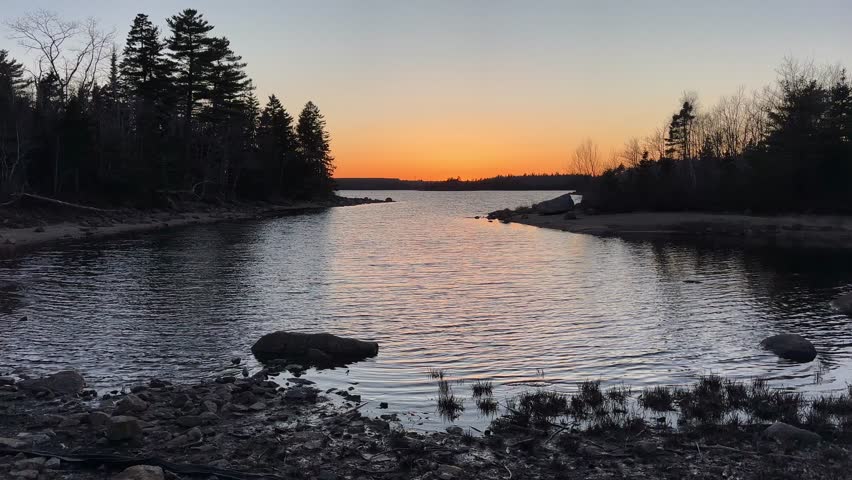 A Beautiful Sunset Over a Lake Near Halifax, Nova Scotia, Canada. The Orange Sky Creates a Stunning Reflection in the Still Water, Surrounded by Forests, Capturing the Tranquility of Nature.
