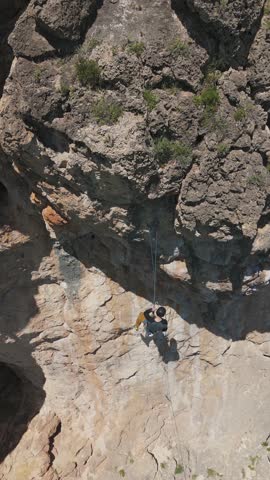 Rock Climber is Descending on Overhanging Crag. Aerial Drone Shot. Vertical Video