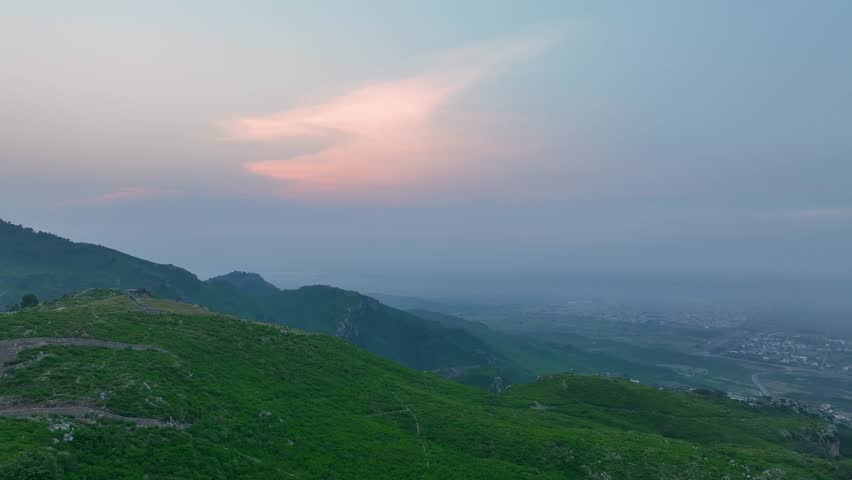Drone view of Islamabad’s Margalla Hills at sunrise, golden light over green forests and hills, a breathtaking natural landscape perfect for travel, nature, scenic visuals, and tourism.
