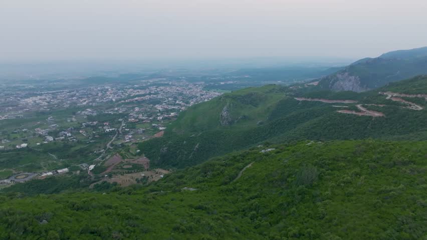 Drone view of Islamabad’s Margalla Hills at sunrise, golden light over green forests and hills, a breathtaking natural landscape perfect for travel, nature, scenic visuals, and tourism.

