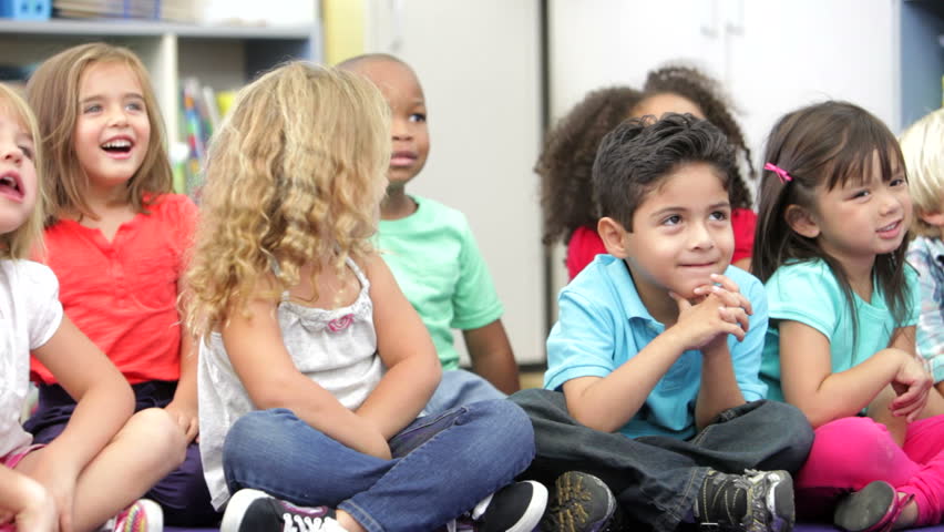 Group of students sitting on floor and listening to off camera teacher. Shot on Canon 5d Mk2 with a frame rate of 30fps