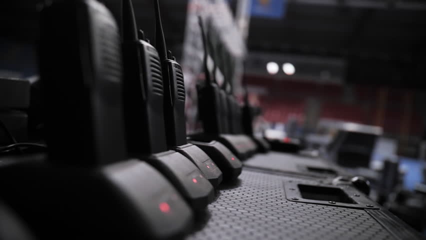 Row of walkie talkies charging at event backstage