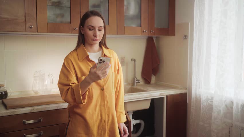 Homeowner woman is making a video call with her smartphone to show a broken sink drain to a plumber, explaining the problem and asking for assistance