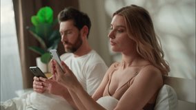 Internet addiction family problem Caucasian married couple lying bed guy husband girl wife hold mobile phones cellphones partners ignoring man woman scroll social media cyberspace apps at home morning - Powered by Shutterstock - Get 15% off with code: PIKWIZARD15