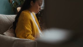 Tilt up shot of little Asian daughter sitting next to young mother working on laptop at home office - Powered by Shutterstock - Get 15% off with code: PIKWIZARD15