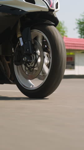 Contemporary motorcycle vehicle drives fast along empty plain road on large city highway on sunny spring day slow motion close view