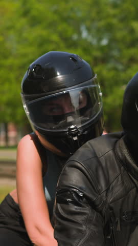 Young woman with helmet hugs boyfriend riding powerful motorcycle together along large city street on sunny spring day closeup slow motion