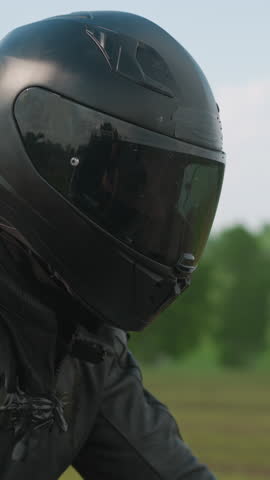 Graceful woman hugs beloved boyfriend motorcyclist riding motorbike along road past green field at country site extreme closeup slow motion
