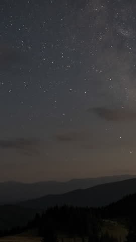 Time lapse of Starry night sky over mountains, Clear starry night sky over silhouetted mountains in peaceful wilderness. Vertical footage