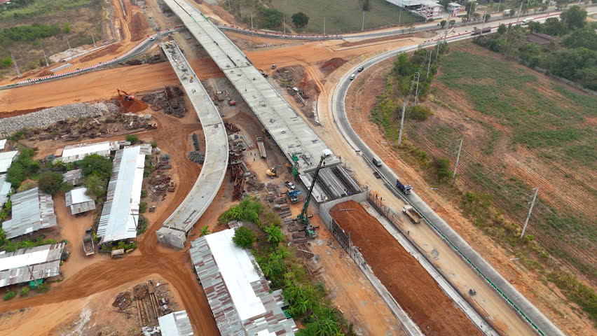 Drone footage Aerial view of highway overpass construction site with machinery, trucks, and infrastructure development in progress. Concept of civil engineering and transportation projects